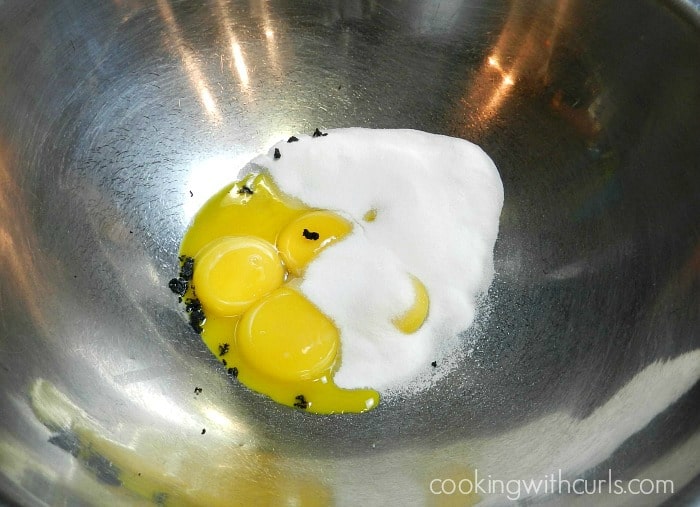 Eggs, sugar and vanilla bean paste in a stainless steel bowl. 