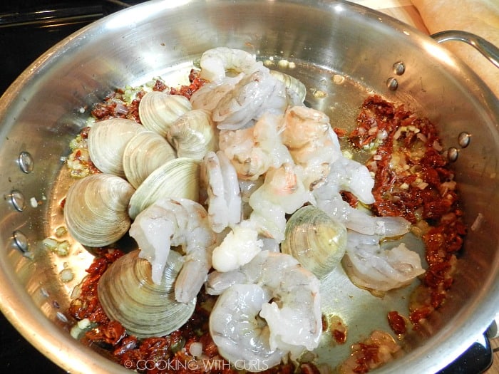 Raw seafood added to the frying pan with the sun-dried tomatoes, garlic and shallots. 
