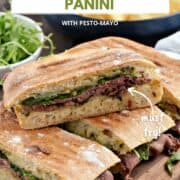 Roast beef panini sandwiches stacked on top of each other on a wooden board with potato chips in the background and title graphic across the top.