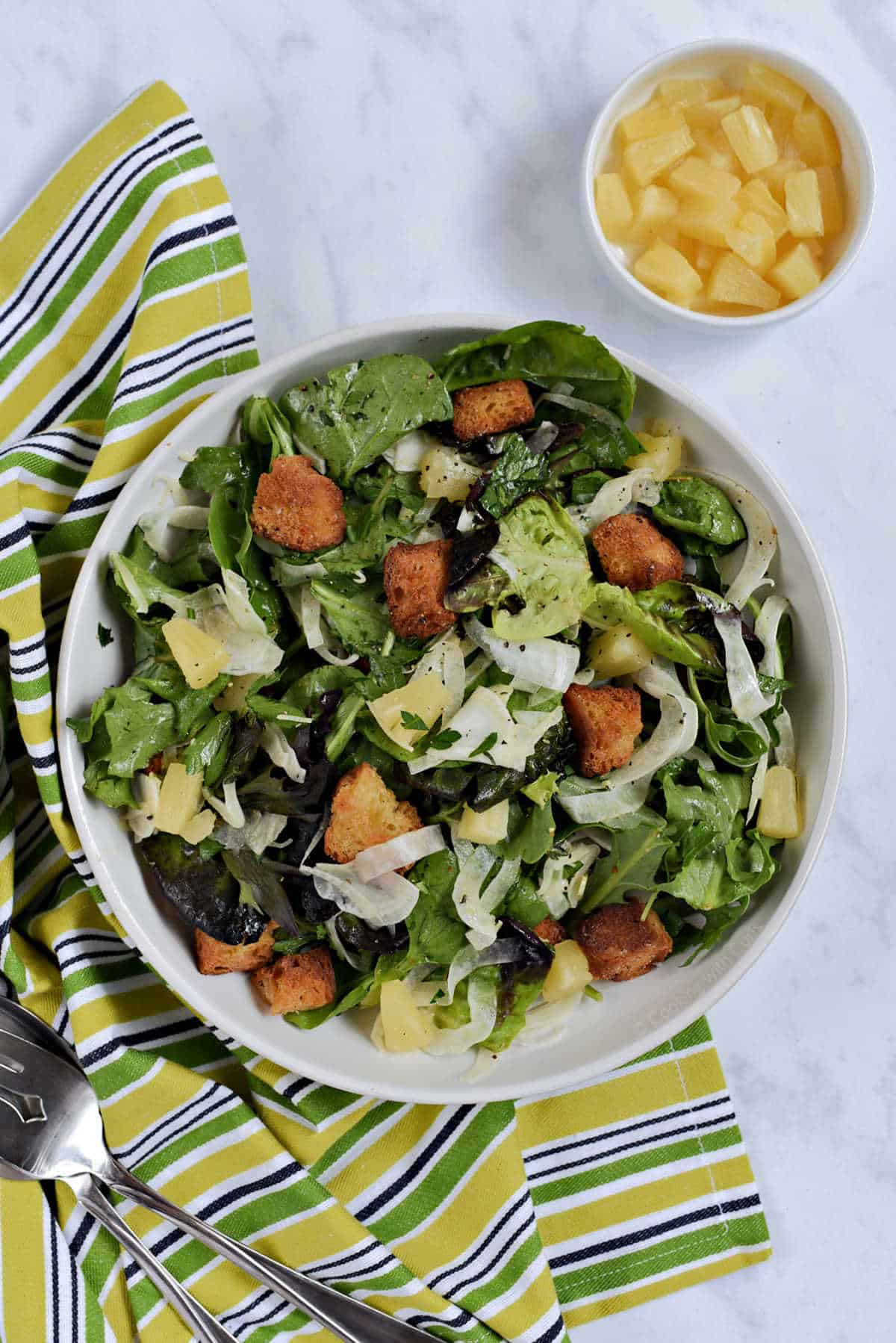 Shaved fennel salad with pineapple chunks, mixed greens, and croutons.