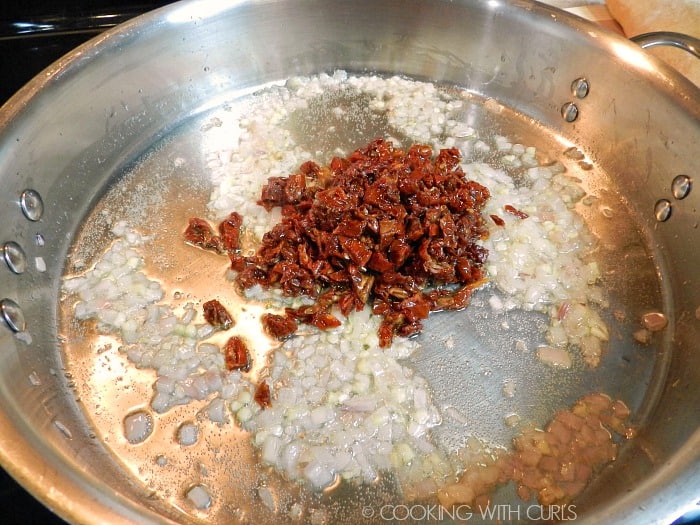 Sun dried tomatoes added to the cooked garlic and shallots in a large frying pan. 