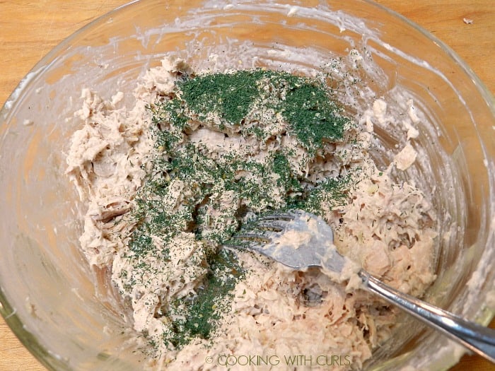 Tuna mixture with mayonnaise and dill weed in a glass bowl. 