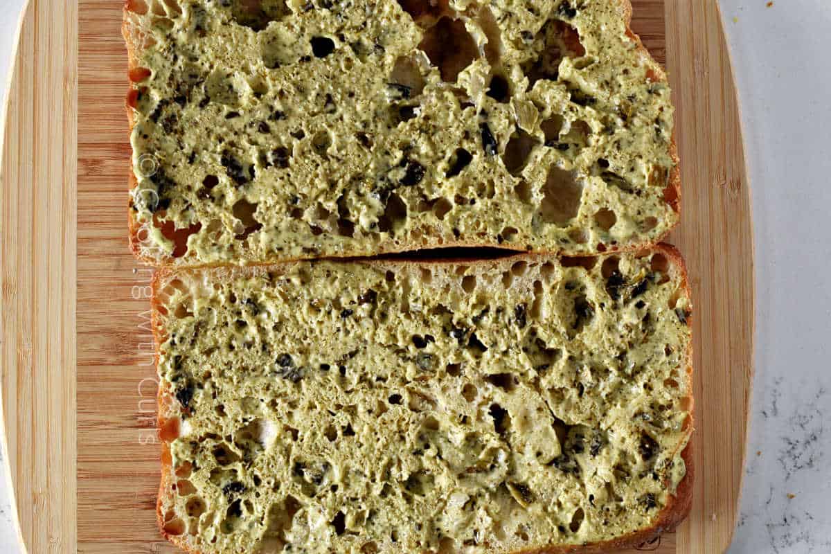 Pesto mayo spread over sliced ciabatta bread.