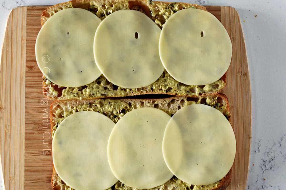 Six sliced of provolone cheese on the pesto mayo bread.