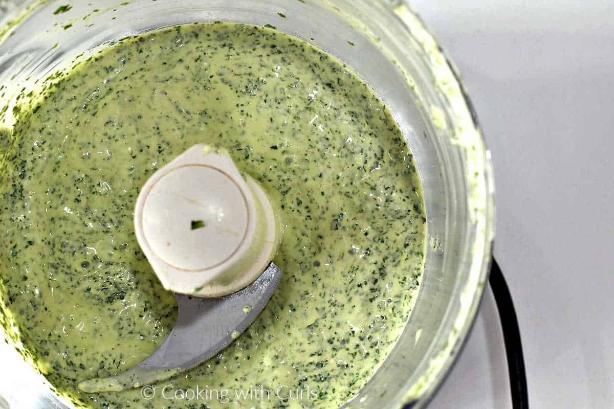 Blended creamy cilantro-lime dressing in a food processor bowl.