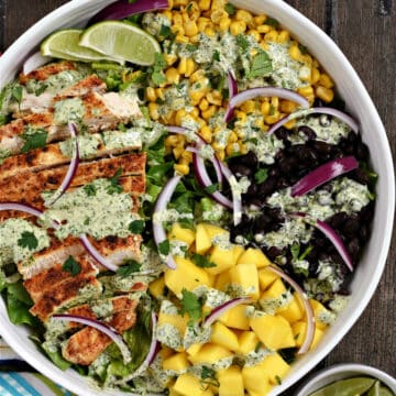 Southwest Chicken Salad with corn, black beans, mango chunks, and red onion slices topped with creamy cilantro lime dressing.