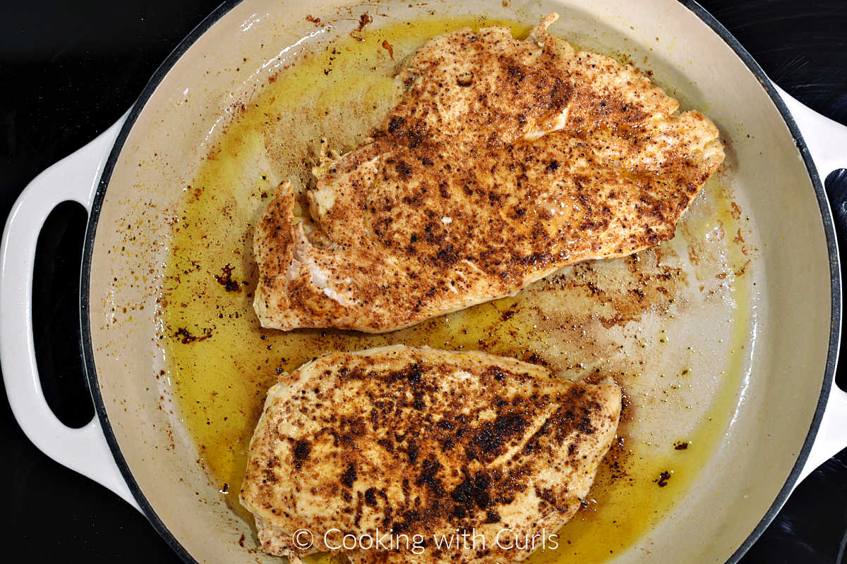 Seasoned chicken breasts cooked in a large skillet.