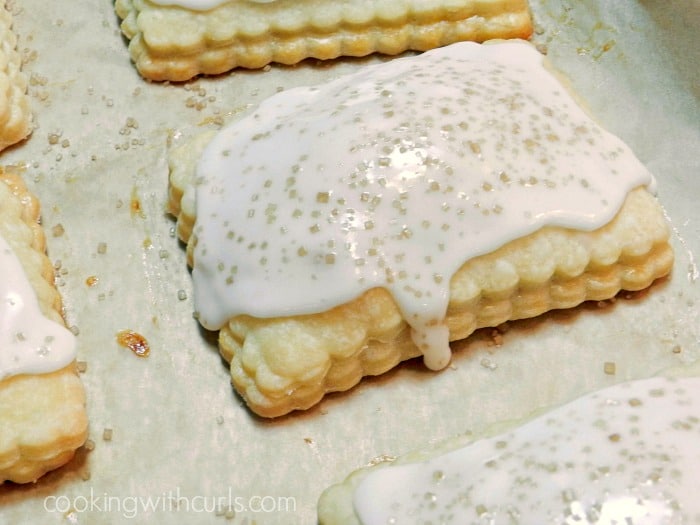 glaze poured over the top of the baked pop tarts on a parchment lined baking sheet, with raw sugar sprinkled on top. 