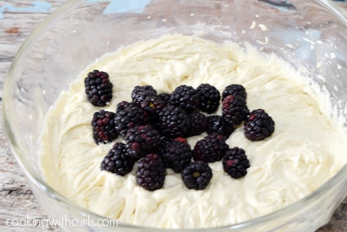 Blackberries laying on top of muffin batter.