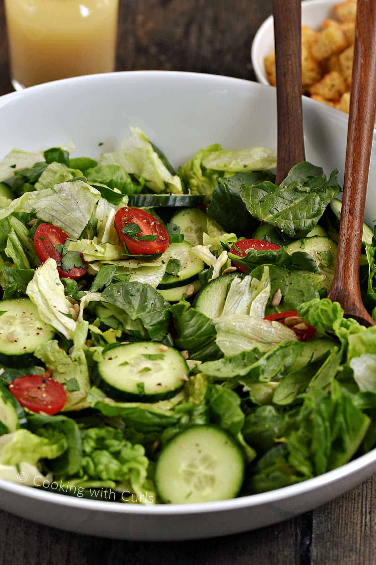 Tossed-Green-Salad-in-a-large-serving-bowl-with-wood-serving-spoons.