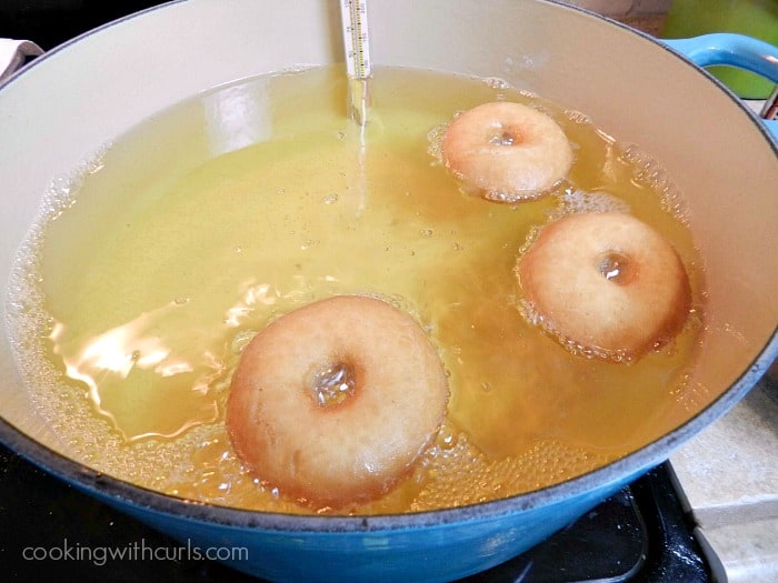 doughnuts frying in hot oil in a large blue pot