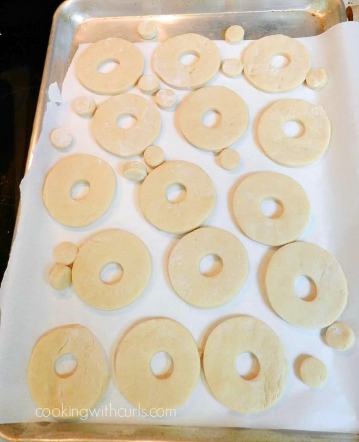 Doughnut holes and cut outs on a parchment paper lined baking sheet.
