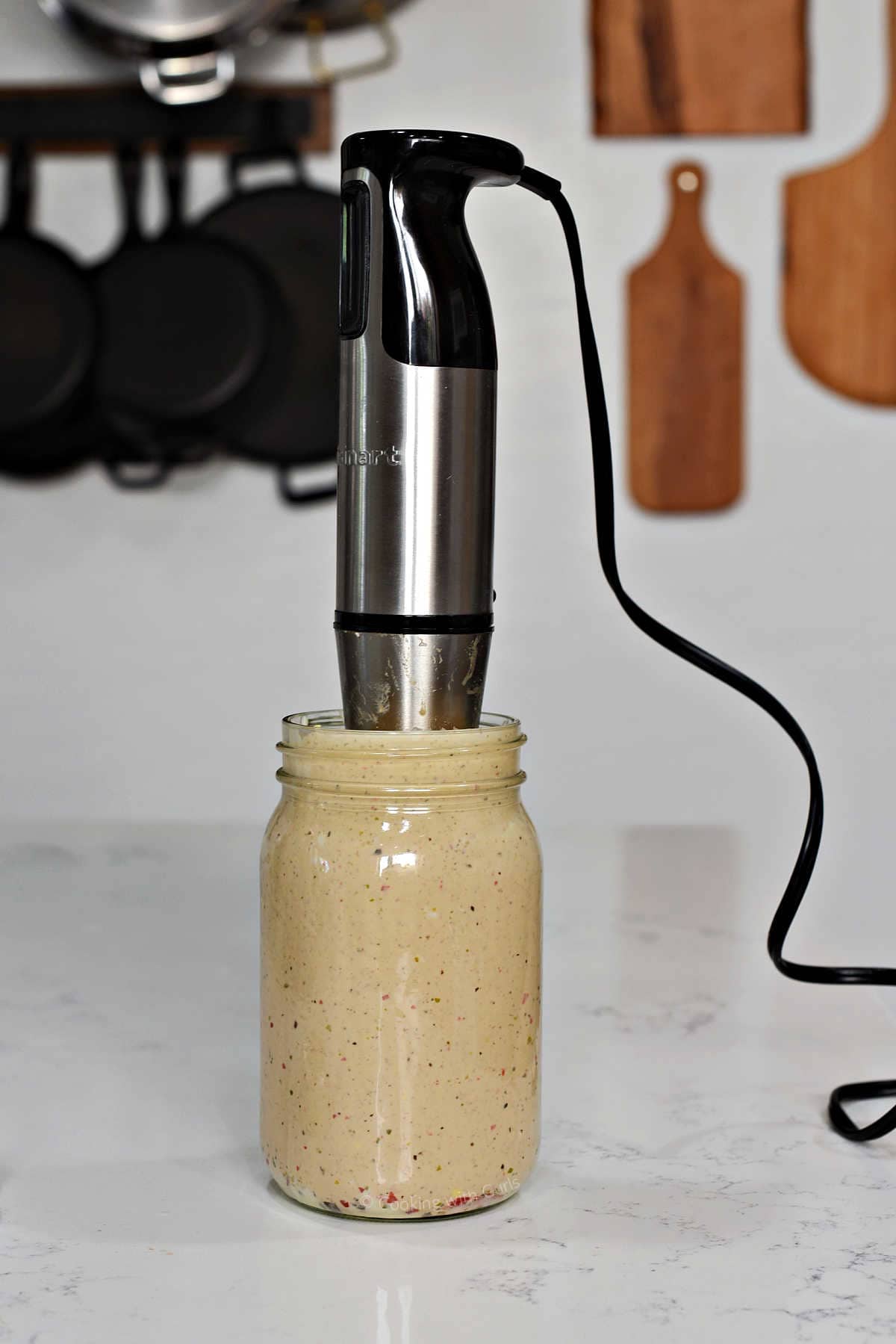 Thousand island dressing in a mason jar being blended with a stick blender.
