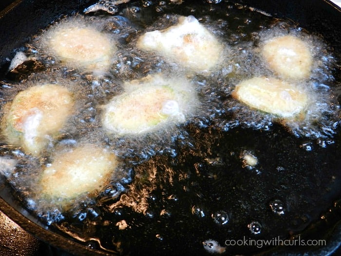 Zucchini Fritters frying in a cast iron skillet 