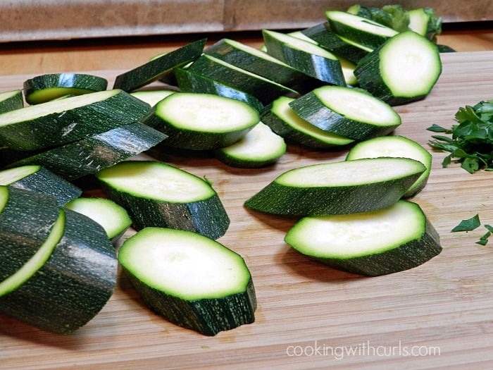 zucchini sliced on the diagonal laying on a bamboo cutting board