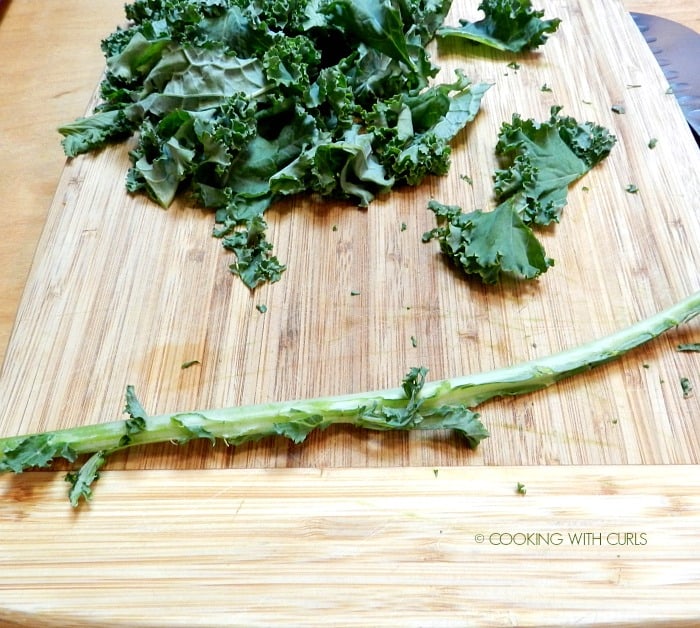 Chopped kale on a wood cutting board with the stem removed