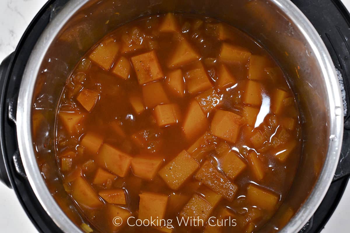 Cooked butternut squash pieces and liquid in a pressure cooker. 