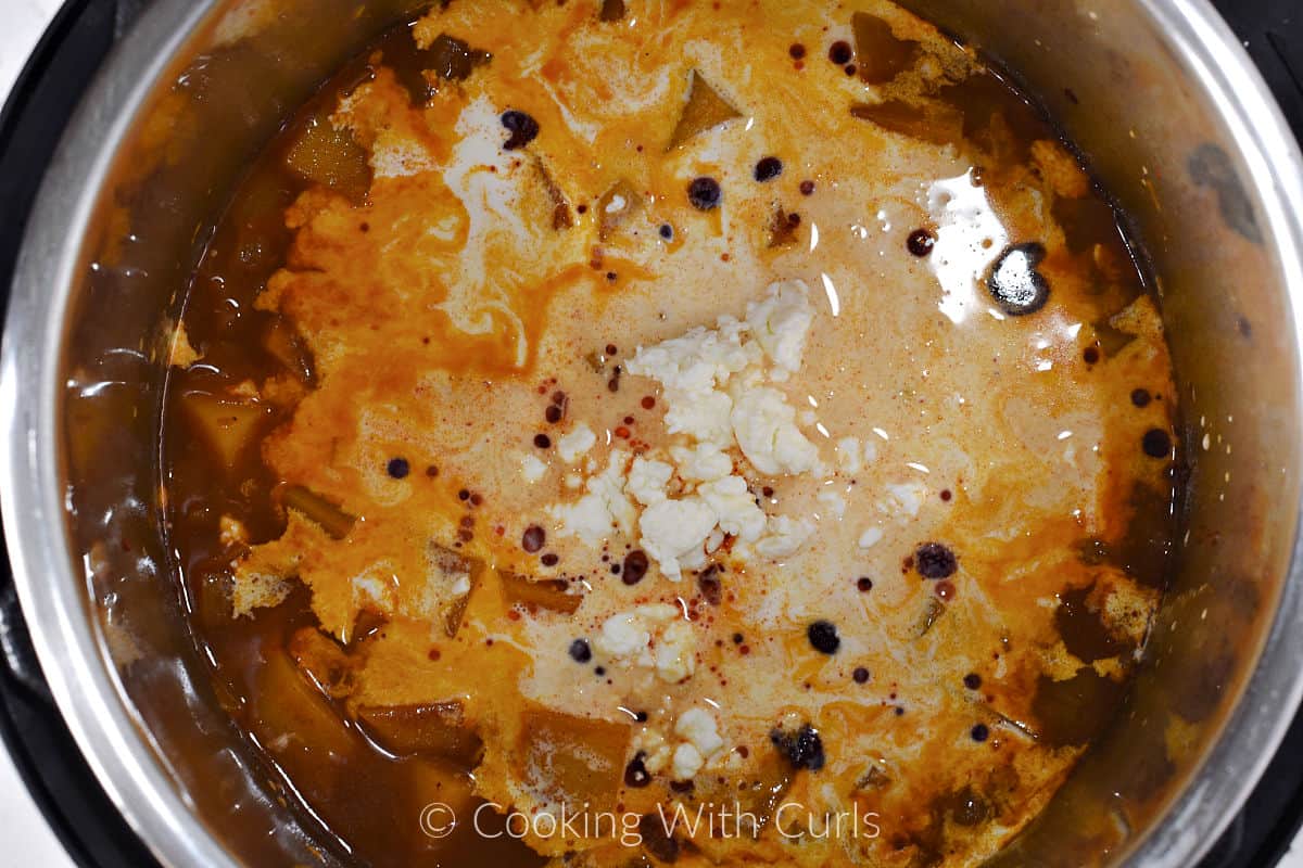 Cream and crumbled feta added to the cooked butternut squash soup in a pressure cooker. 