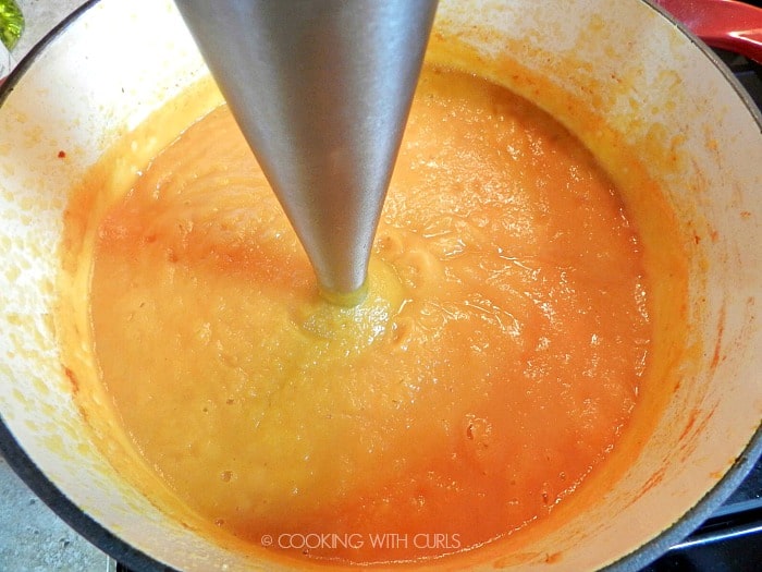 Butternut Squash Soup being pureed with an immersion blender in a large pot.