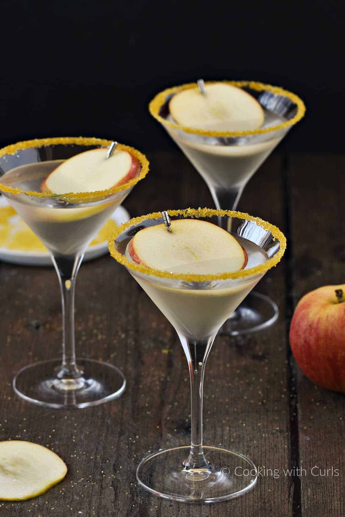 Three caramel apple martinis in sugar rimmed martini glasses.