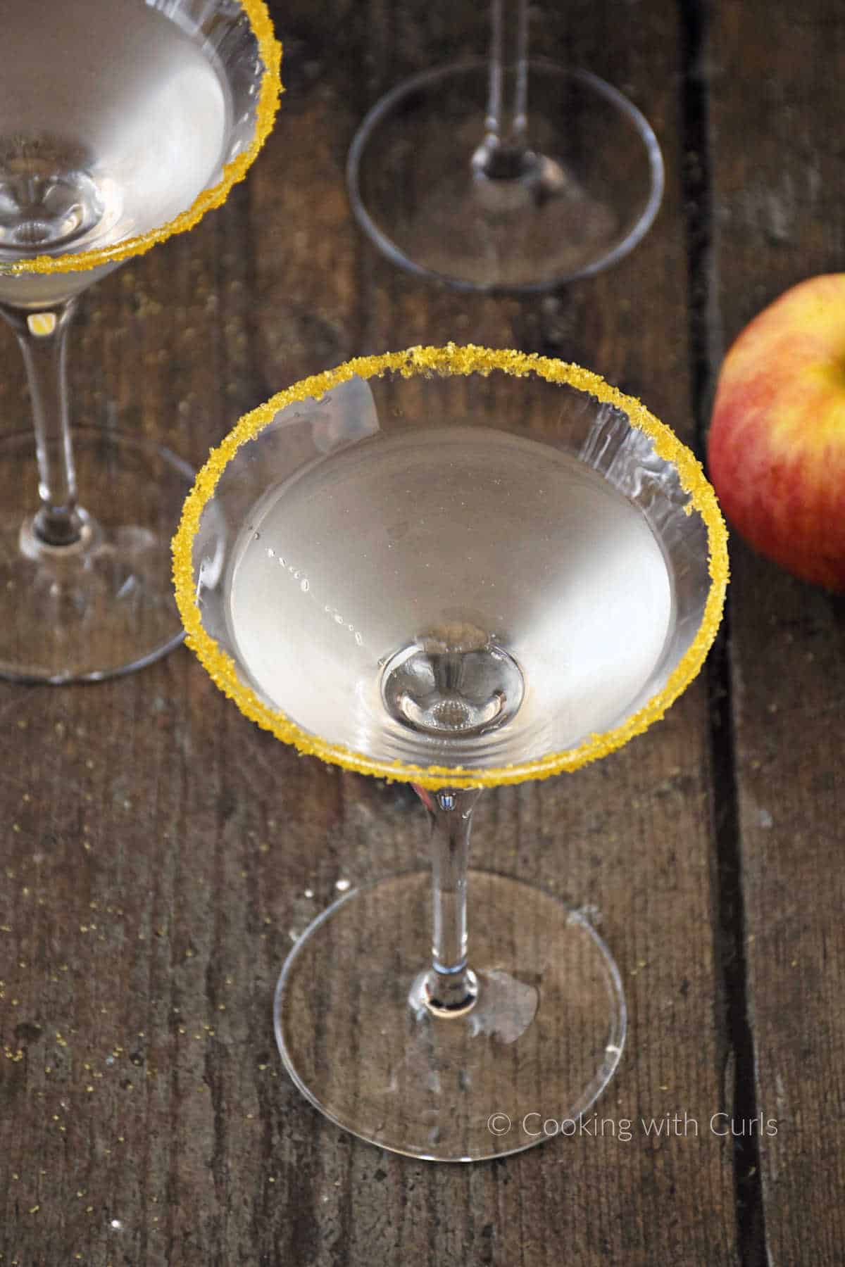Clear caramel apple cocktail in a sugar rimmed martini glass.