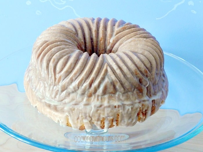 gingerbread martini bundt cake sitting on a glass cake pedestal with a blue background