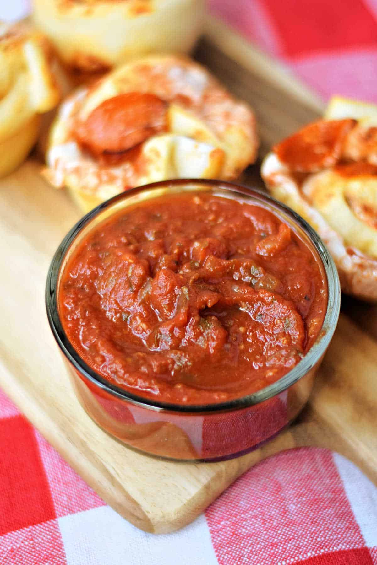 Homemade pizza sauce surrounded by pepperoni pizza rolls.