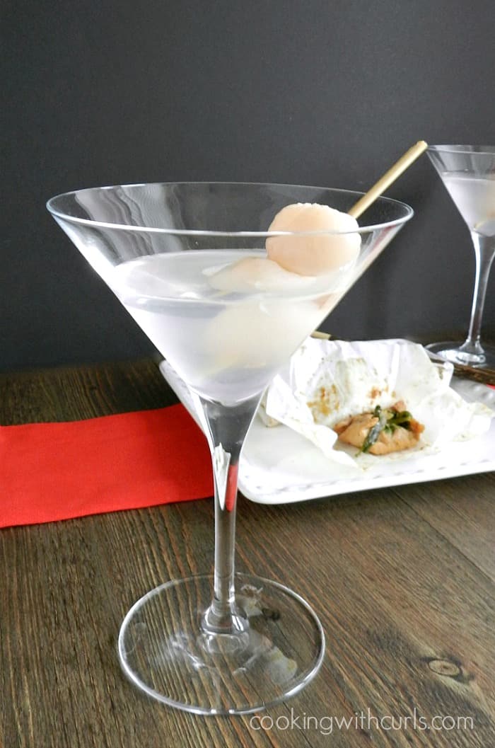 Martini glass filled with a lychee martini and a toothpick inserted into two lychees.