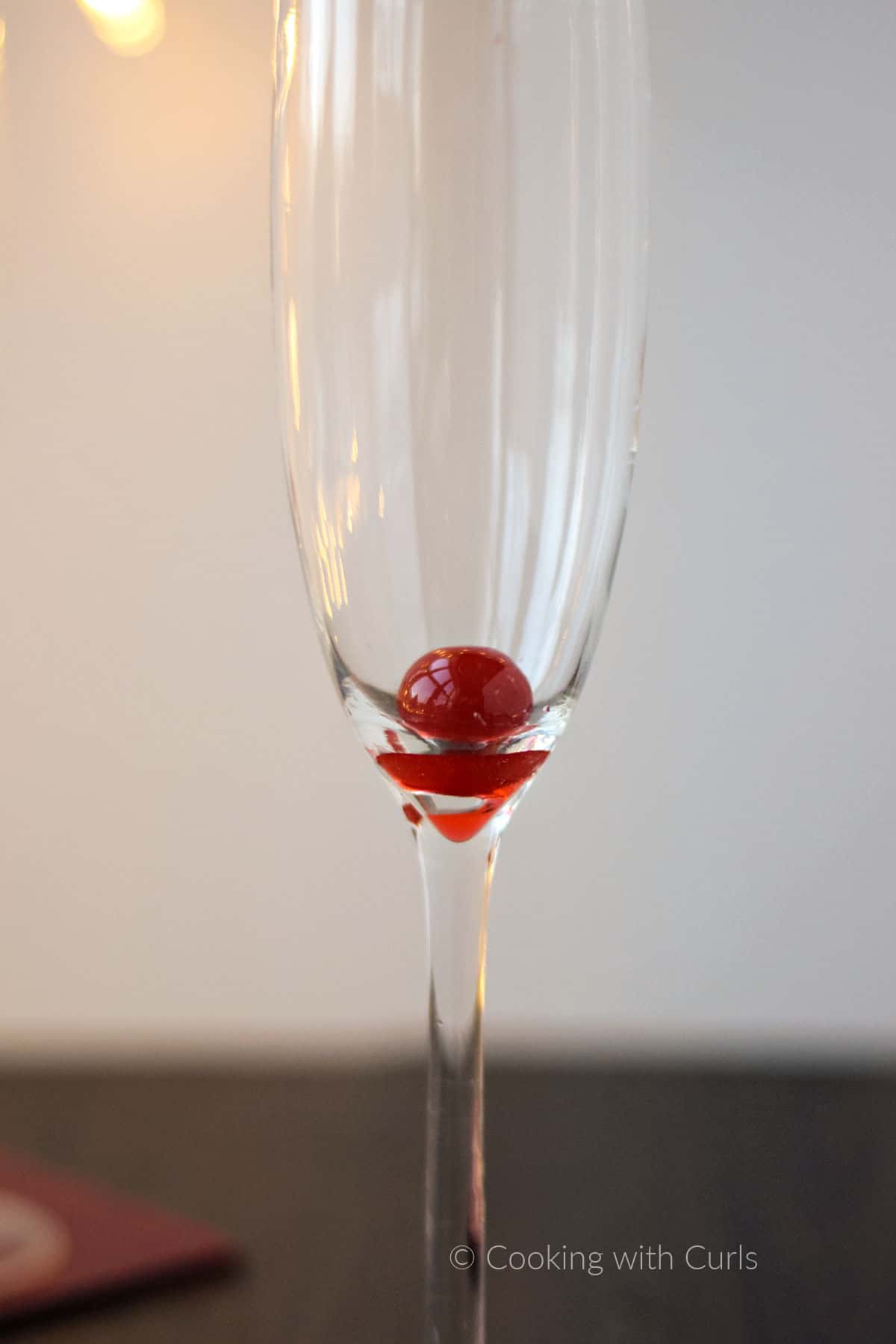 A maraschino cherry at the bottom of a champagne flute. 