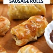 Looking down on seven sausage rolls on a wood platter with a small bowl of sauce and title graphic across the top.