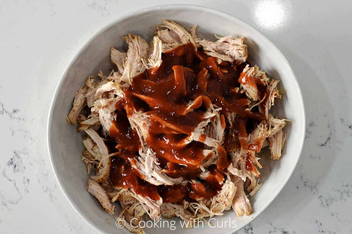 Shredded chicken and taco sauce in a mixing bowl.