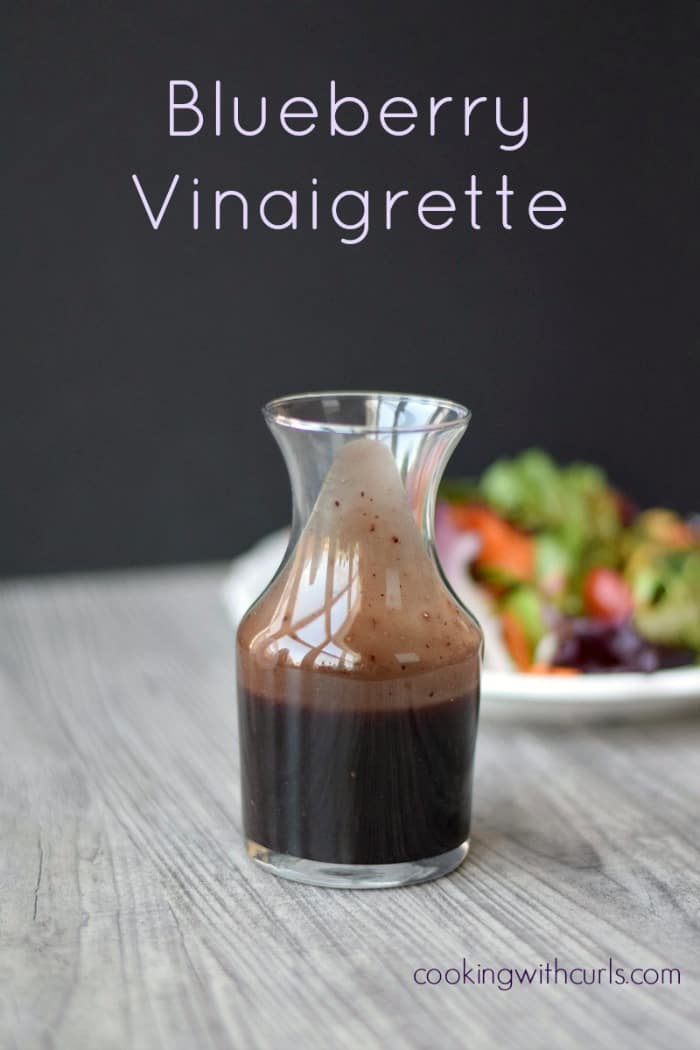 A super simple Blueberry Vinaigrette in a glass jar with a salad in the background