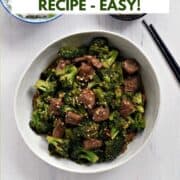 Strips of beef and broccoli florets coated in sauce and sprinkled with sesame seeds in a large bowl with title graphic across the top.