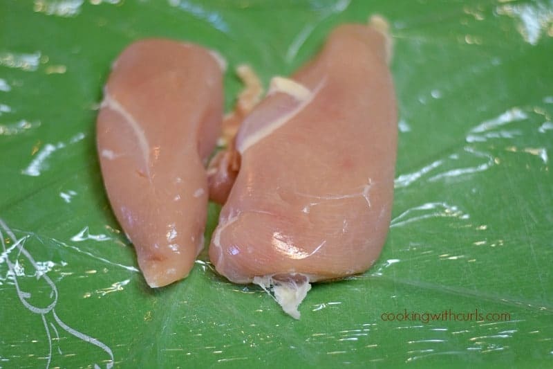 two chicken breasts on a green cutting mat