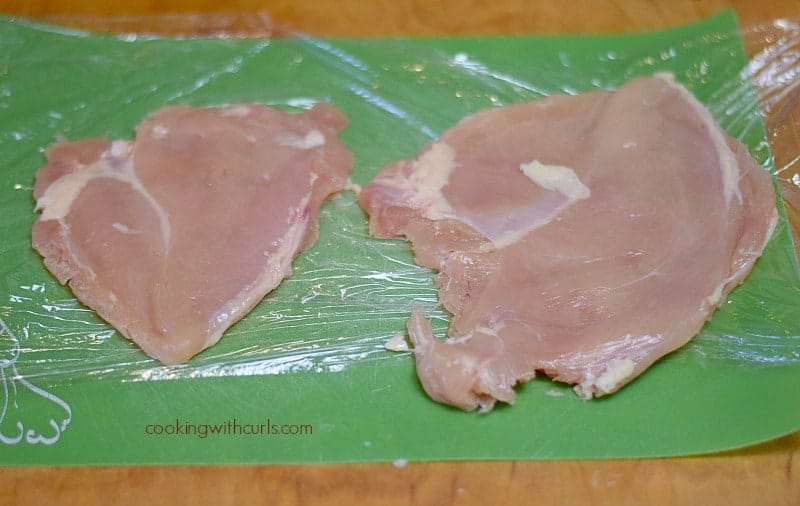 two flattened chicken breasts on a green cutting mat