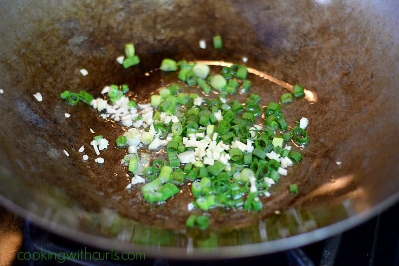 Oil, garlic, and green onions in a wok.