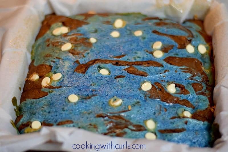 Baked blue swirled cream cheese brownies with white chocolate chips pushed randomly into the top to look like stars.