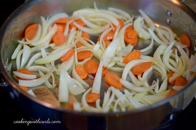 Sliced carrots and onions in a large skillet.