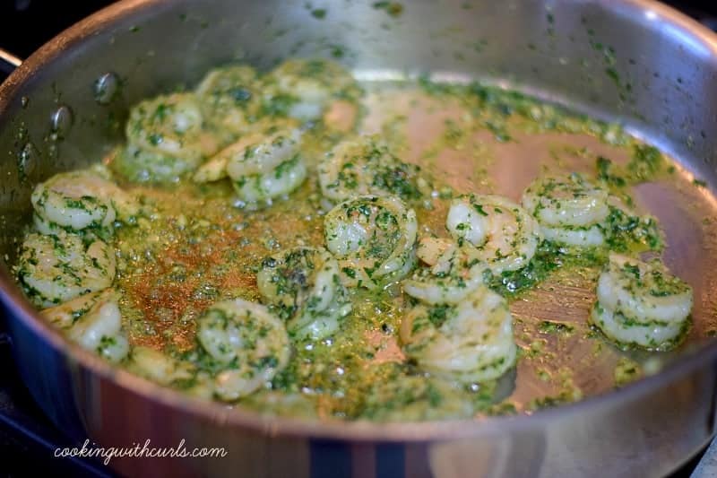 Shrimp and pesto sauce in a large skillet.