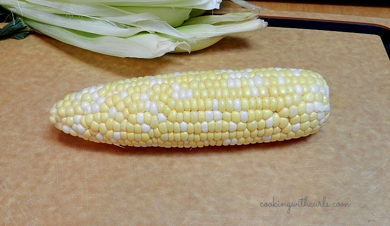 fresh corn sitting on a cutting board