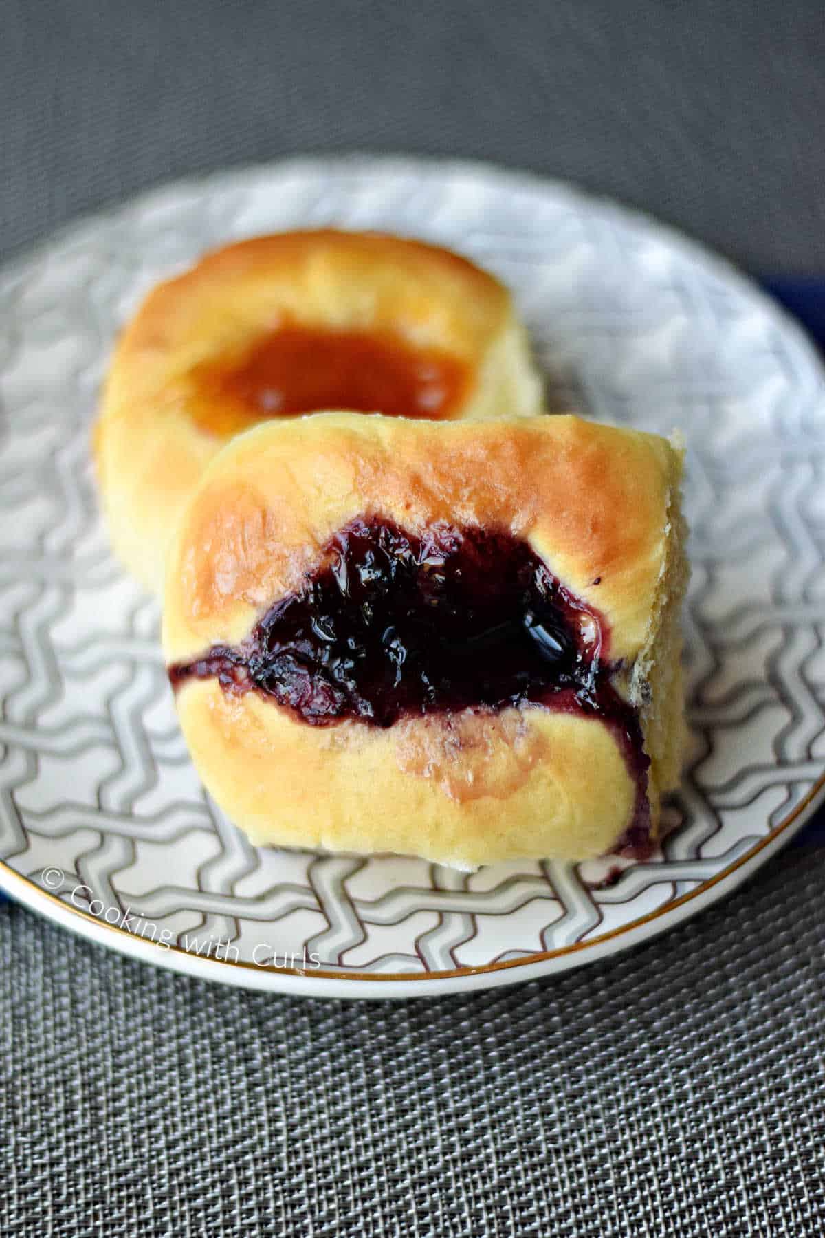 One traditional blueberry kolache and one apricot on a plate.
