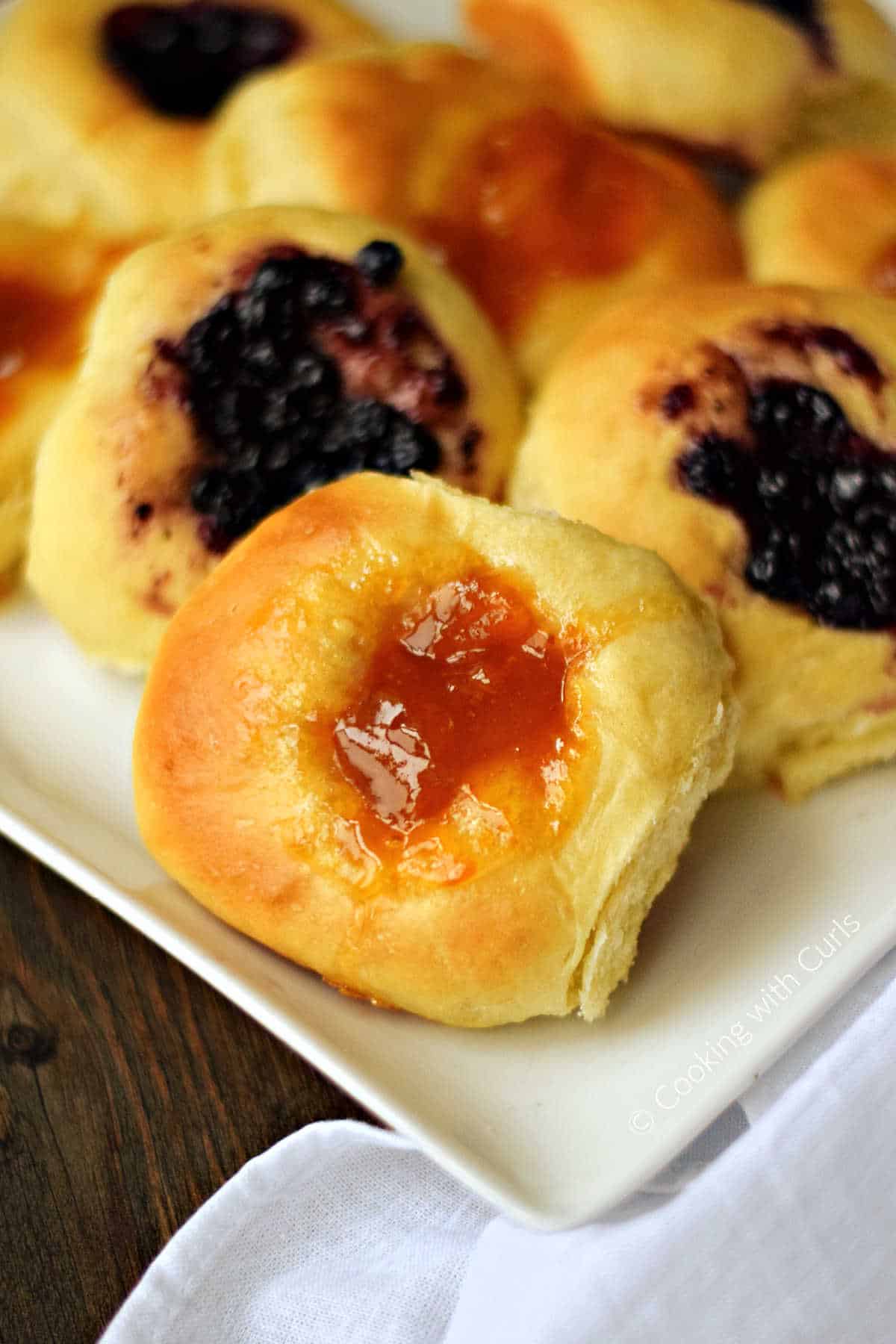 A plate full of blueberry and apricot kolaches.