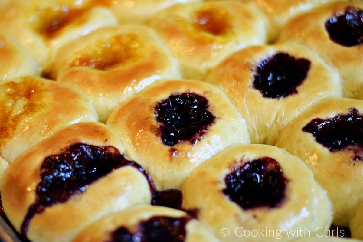 Baked blueberry and apricot kolaches on a baking sheet.