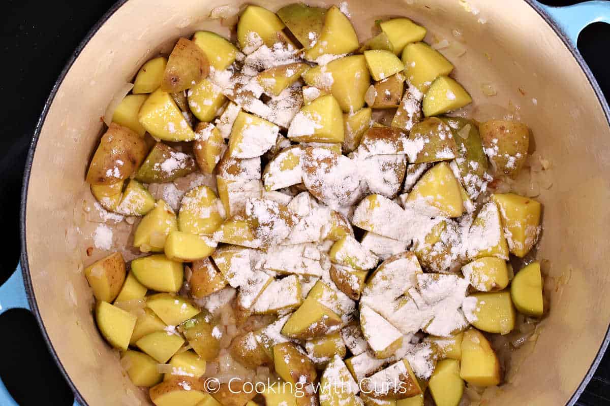 Flour sprinkled over chopped potatoes in a large pot. 