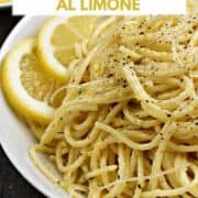 Spaghetti with lemon sauce in a bowl with lemon slices and sprinkled with black pepper and parmesan cheese with title graphic across the top.