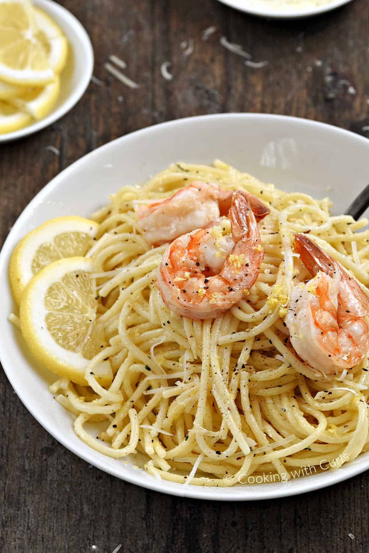 Spaghetti al Limone topped with cooked shrimp in a bowl.
