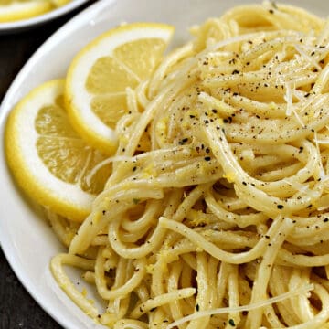 Spaghetti with lemon sauce in a bowl with lemon slices and sprinkled with black pepper.