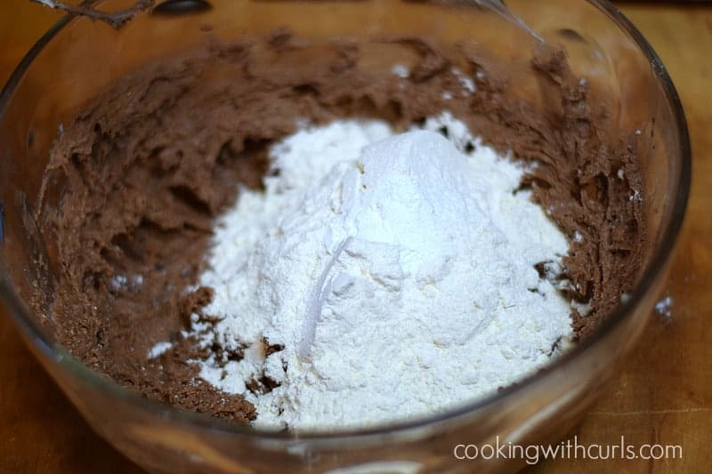 flour added to the chocolate cookie mixture in the glass bowl