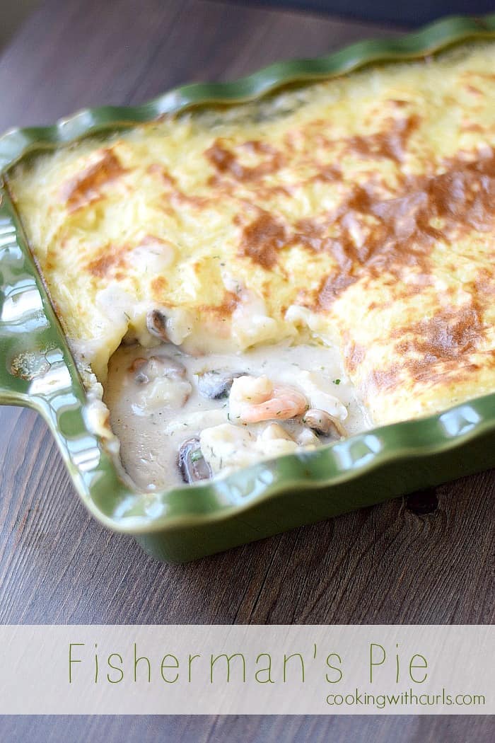 mashed potato topped fish pie in a dark green baking dish sitting on a dark brown table
