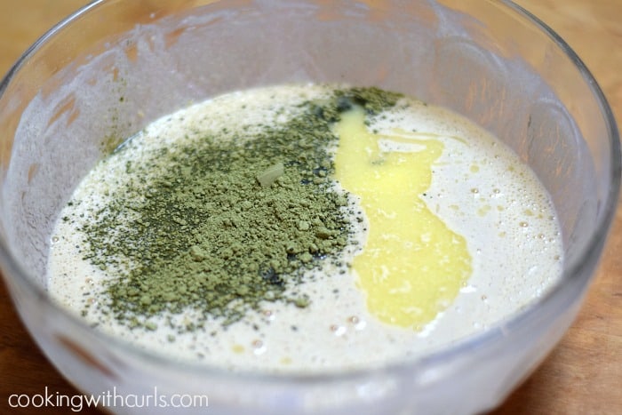 Milk, matcha powder, and butter in a large glass bowl.